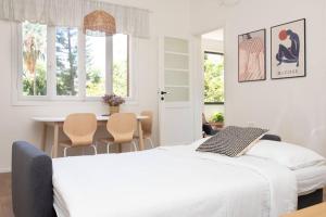 a bedroom with a white bed and a table with chairs at Bright and Cozy Bauhaus Gem in Ra‘ananna