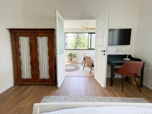 a bedroom with a bed and a desk and a door at Bright and Cozy Bauhaus Gem in Ra‘ananna