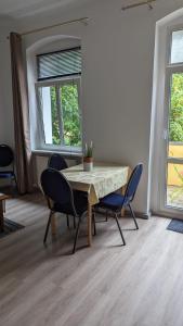 a dining room with a table and chairs and two windows at Pension Hubertus in Berlin