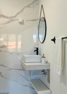 a white bathroom with a sink and a mirror at Feeling Like Home Machico in Machico
