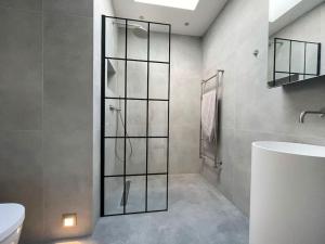 uma casa de banho com um chuveiro, um WC e um lavatório. em Stunning, architecturally designed Garden Studio with Parking em Londres