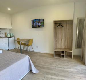 a bedroom with a bed and a table and a kitchen at Feeling Like Home Machico in Machico