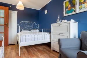 a blue bedroom with a white crib and a blue wall at Dom Kotwa in Karwia