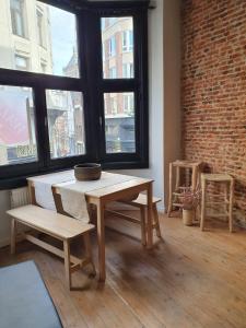 een tafel en stoelen in een kamer met een bakstenen muur bij Den Gulden Hoorn in Antwerpen