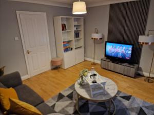 a living room with a couch and a tv at What a great location in Bromley with 4 bedrooms! in Bromley