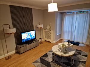 a living room with a television and a table at What a great location in Bromley with 4 bedrooms! in Bromley