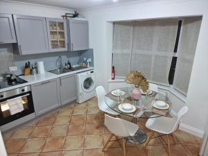 cocina con mesa de cristal y armarios blancos en What a great location in Bromley with 4 bedrooms!, en Bromley