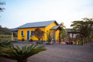 a yellow house with a blue roof and a yard at Pousada Nonno Fiorindo in Volta Grande