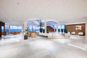 un vestíbulo de oficina con una escalera, mesas y sillas en Hotel Best Semiramis, en Puerto de la Cruz