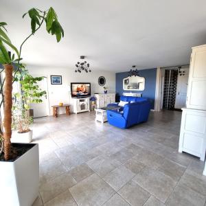 ein Wohnzimmer mit einem blauen Sofa und Fliesenboden in der Unterkunft Belvédère du midi in Ayguesvives