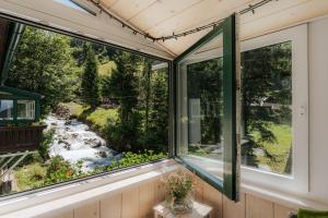 ein Fenster in einem Haus mit Blick auf einen Wasserfall in der Unterkunft Ferienwohnungen Badbruckerweg- Bad Gastein in Bad Gastein
