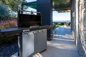a outdoor grill with a smoker on a patio at LUXURY VILLA ORIZZONTI - Regarda Travel in Bardolino