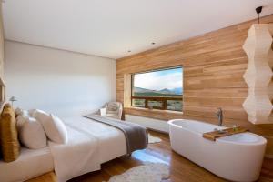 1 dormitorio con cama, bañera y ventana en Tierra Patagonia, en Torres del Paine