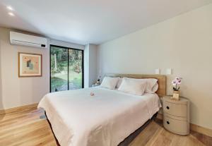 a bedroom with a large white bed and a window at The Somos Flats Central Poblado in Medellín