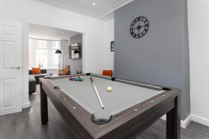 uma sala de estar com uma mesa de bilhar e um relógio em Flatzy - 12 Person Townhouse with Pool Table and Ping Pong em Liverpool