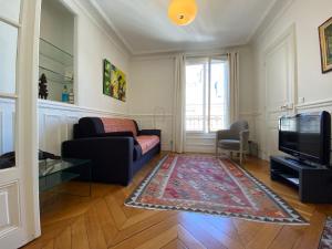 uma sala de estar com um sofá e uma televisão em Nice Sunny Central Paris em Paris
