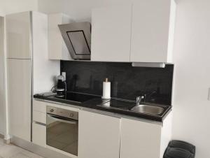 a white kitchen with a sink and a refrigerator at Agréable Studio calme 2 pers in Saint-Quentin