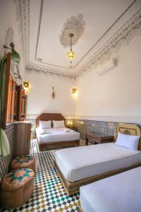 a hotel room with two beds and a checkerboard floor at Dar Elinor in Fès