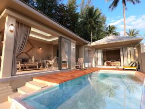 a house with a swimming pool and a patio at Devasom Khao Lak Beach Resort & Villas in Khao Lak