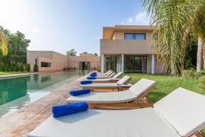 a row of lounge chairs next to a swimming pool at Villa Marrakech Palmeraie Lux in Marrakech