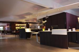 a restaurant with a bar with tables and chairs at Mercure Hexagone Luxeuil in Luxeuil-les-Bains