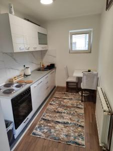 - une cuisine avec des placards blancs, une cuisinière et un tapis dans l'établissement Dino Sarajevo Apartment, à Sarajevo