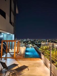 大坎普的住宿－Studio Bali，一个带椅子的阳台,晚上提供游泳池