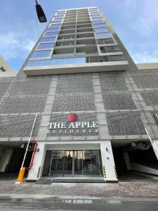 Un edificio con l'insegna di mele sul lato. di The Apple Residence a Juffair
