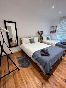 a bedroom with two beds and a mirror at Notting Hill Guest Flat in Ealing
