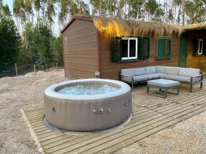 una vasca idromassaggio su una terrazza in legno con una casa di Montum Farm Living a Melides