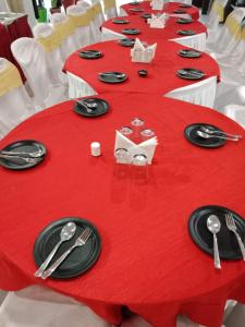 a long red table with black plates and silverware on it at HOTEL R K PALACE in Bhopal