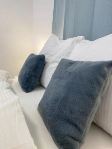 zwei blaue Kissen auf einem weißen Bett in der Unterkunft LUX Apartments in Mörfelden-Walldorf