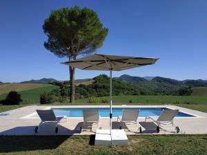 un grupo de sillas y una sombrilla junto a una piscina en Villa Paola Holidays en SantʼAngelo in Vado