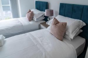 two beds in a bedroom with white sheets and pillows at The Sidings, Luxury Penthouse, Haworth in Haworth