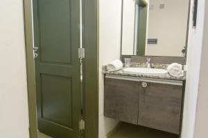 a bathroom with a sink and a mirror and a door at Apart Hotel Jorge I in Santiago del Estero
