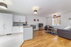 a kitchen and living room with white cabinets and a couch at Lovely 2 BR with patio Waterloo LM1 in London