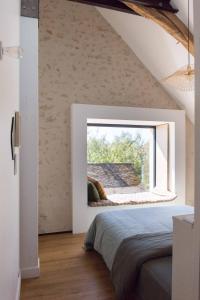 a bedroom with a large window in the attic at Maison d'hôtes le détour en pleine nature in Channay-sur-Lathan