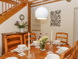 een eetkamer met een houten tafel met borden en kaarsen bij Mountfield Farm Cottage in Wavehorne