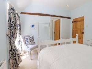 a bedroom with a white bed and a chair at Mountfield Farm Cottage in Wavehorne