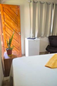 a bedroom with a bed and a wooden door and a chair at Luamar Chalés in São Miguel do Gostoso