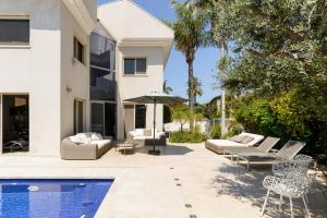 un patio trasero con piscina y una casa en Maison d architecte, en Herzelia 