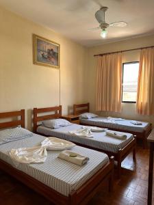 a room with three beds and a ceiling fan at Hotel Bandeirantes de SJBV in São João da Boa Vista