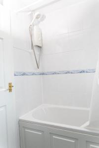 4 bedroom home - free parking by Ideel Apartments in Milton Keynes في Wolverton: حمام أبيض مع حوض استحمام وهاتف على الحائط