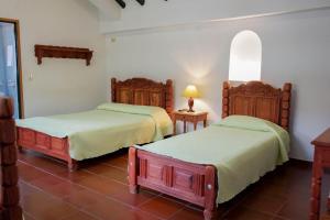 a bedroom with two beds and a lamp on a tile floor at Hotel Beth Sarim By Legendary in Villa de Leyva