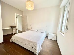 biała sypialnia z łóżkiem i biurkiem w obiekcie santa maria al mare house w Rimini
