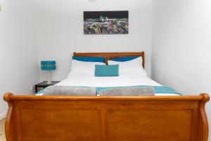 4 bedroom home - free parking by Ideel Apartments in Milton Keynes في Wolverton: غرفة نوم بسرير مع اطار خشبي