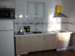 a kitchen with white cabinets and a sink and a microwave at Sabores Hurdanos in Las Mestas