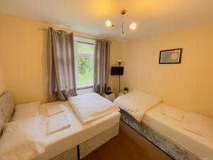 a bedroom with two beds and a window at Three Bedroom House with private car park in London