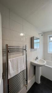 a white bathroom with a sink and a shower at Three Bedroom House with private car park in London