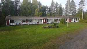 a red and white house on a grass field at Wanha Kaivoskylä Mainari Oy in Kemijärvi